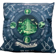 Decorative pillow with a circular design featuring a house and portraits on a blue background.