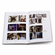 An open hardcover book showing two printed interior design pages with multiple small photographs of rooms and architectural spaces, photographed on a clean white background.