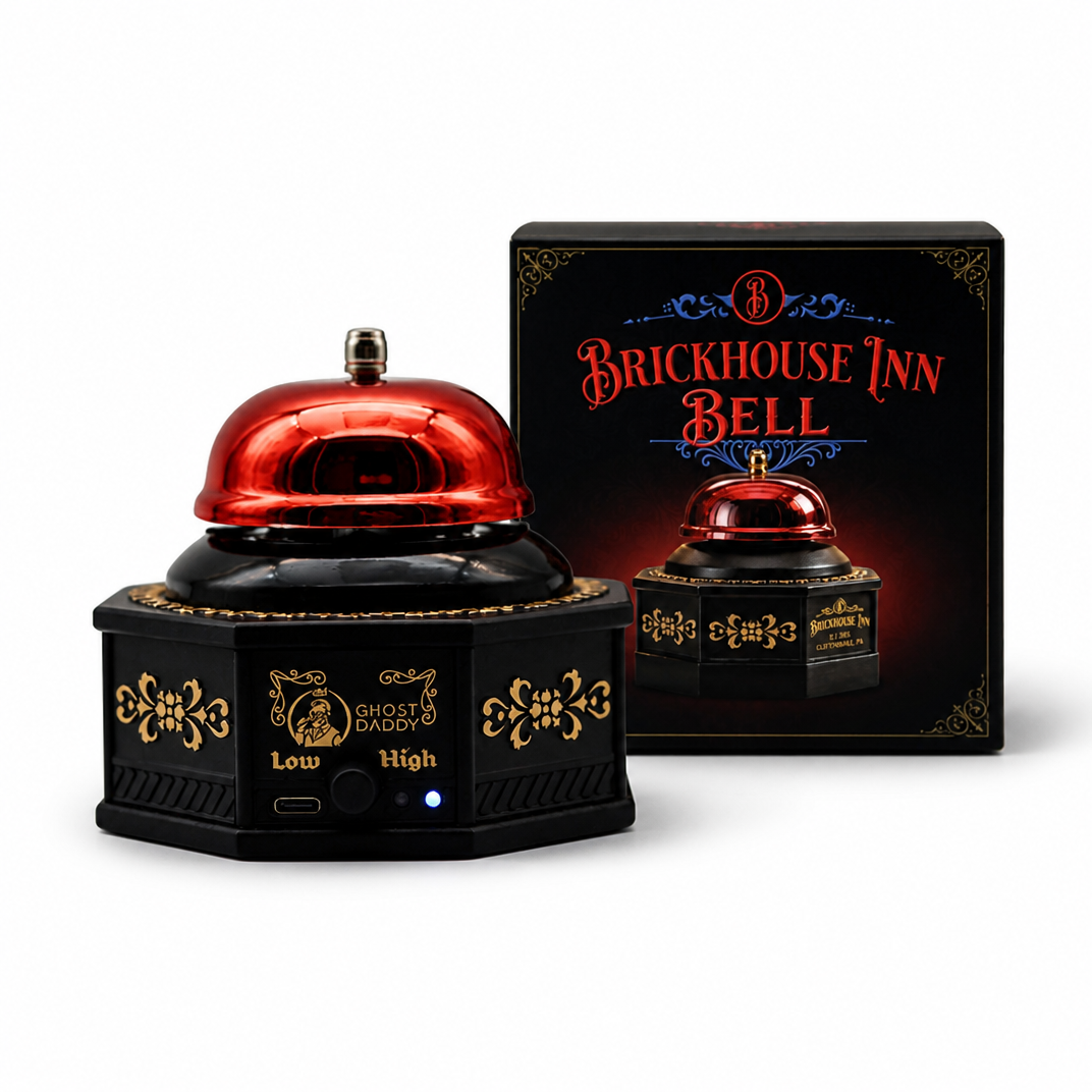 A black and red brick-themed bell machine with gold decorative details, shown alongside its retail box. The product features a glossy red bell on top of a black base with gold accents, and the packaging displays the 'Brickhouse Inn Bell' branding.