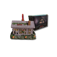 Ornament of a haunted house Lizzie Borden sign, next to its packaging on a white background.